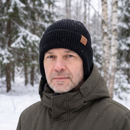 Hue med øreklapper i sort båret i en snedækket skov